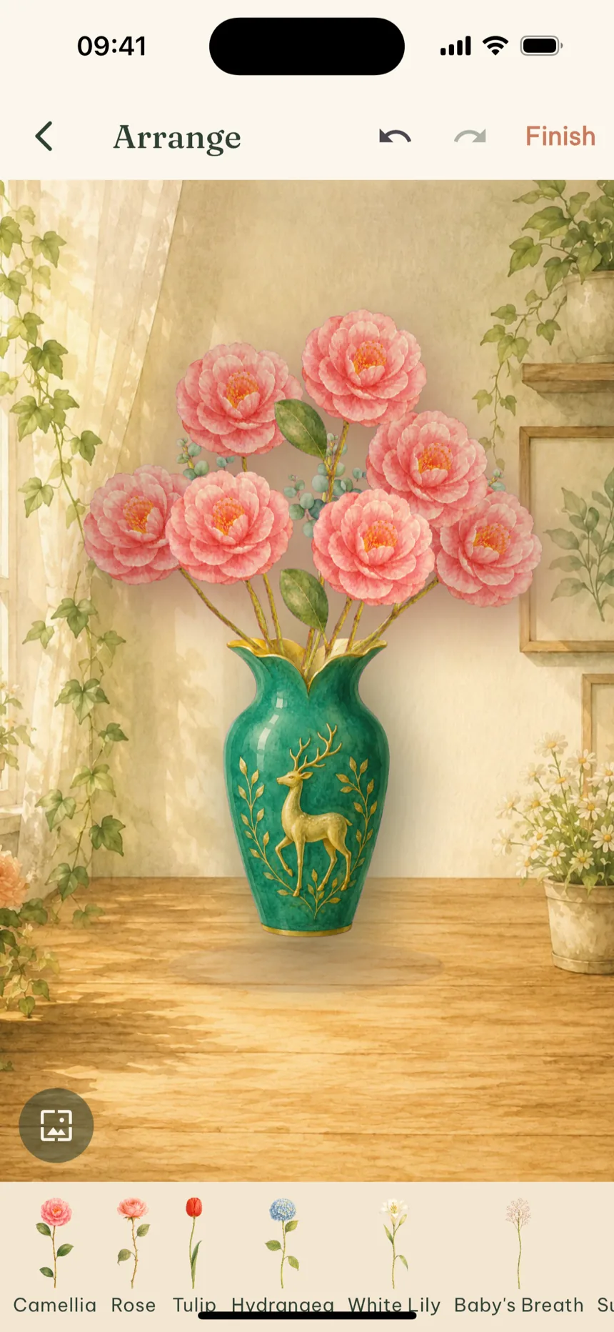 The Bloomette arrange screen: seven pink camellias and eucalyptus in a teal deer vase.